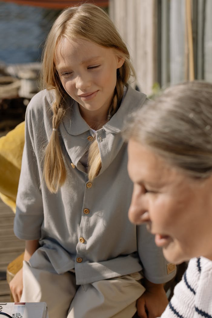gallery-1 Heartwarming moment of a grandmother and granddaughter bonding in a sunny outdoor setting.